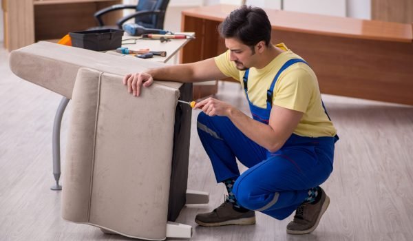 Young male carpenter repairing arm-chair in the office Young carpenter repairing arm-chair in the office